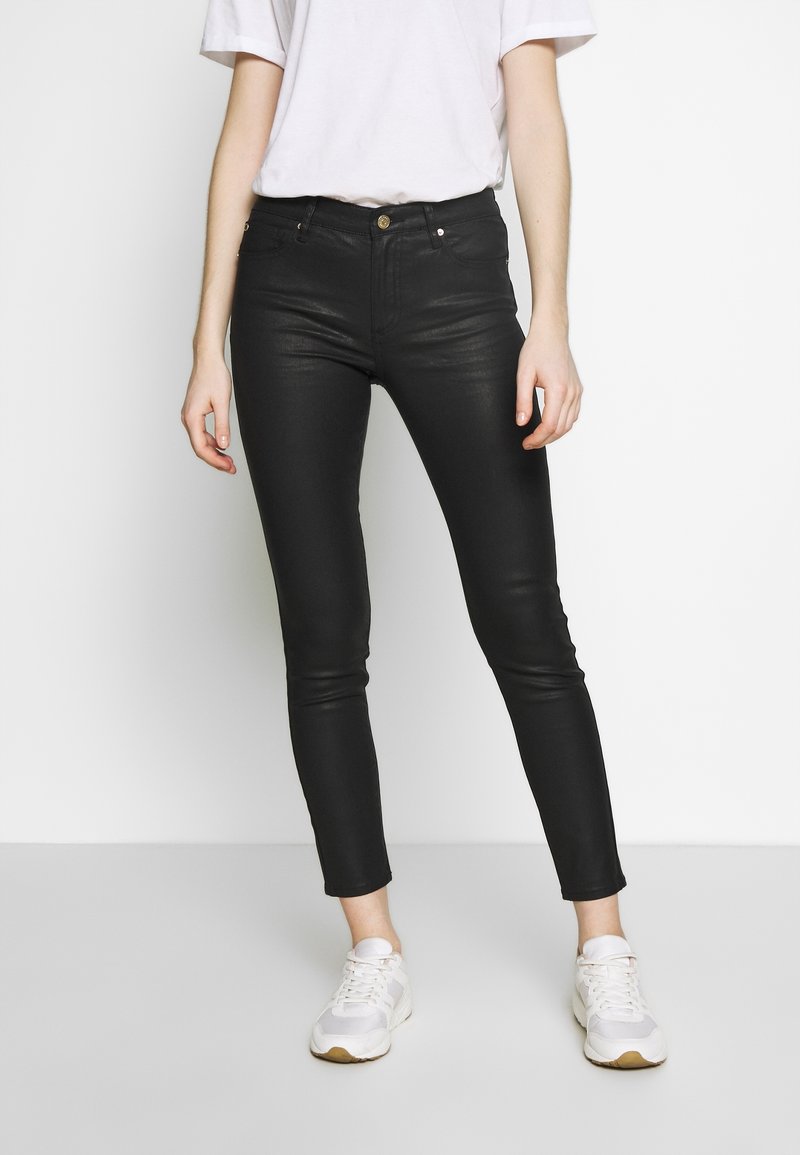 Svarta denim skinny jeans med medelhög midja, fem fickor och en slät yta, i kombination med vita sneakers.