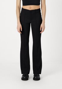 Pantalons noirs ajustés avec un design texturé à côtes, présentant une taille haute et des jambes évasées. Posés à plat, mettant en valeur des coutures soignées et des lignes épurées.