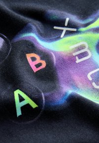 Černá tkanina s barevnými, gradientními písmeny 'A', 'B' a 'X' s hladkým texture a jemným leskem.
