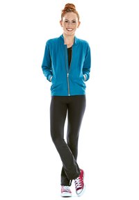 Teal zip-up bomberjacka över en svart topp, matchad med svarta byxor och röda sneakers med vita sulor. Slät tyg och avslappnad passform.