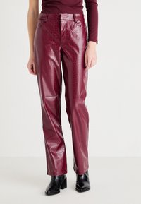 Burgundy konstläderbyxor med krokodilstruktur, med en figurnära midja, raka ben och sidofickor. Stylistiskt kompletterade med svarta klackstövlar.