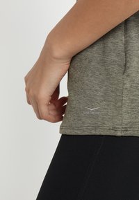 Szaro-zielona koszulka sportowa wykonana z lekkiego materiału, z okrągłym dołem oraz małym logo "Venice Beach" w dolnej części.