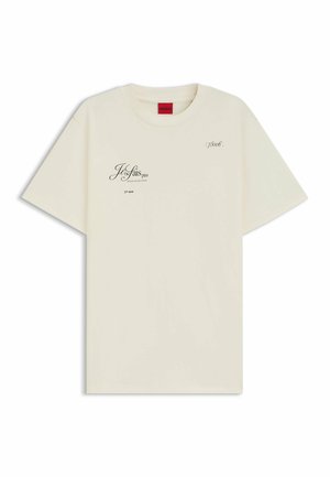 Kremowy bawełniany t-shirt z krótkim rękawem. Posiada nadrukowany tekst i czarne akcenty graficzne. Design z okrągłym dekoltem, luźny krój.