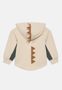 Παιδικό μπεζ φούτερ με κουκούλα, με σκούρες πράσινες πλαϊνές πλευρές και καφέ αγκάθια δεινοσαύρου στην κουκούλα και στο πίσω μέρος.