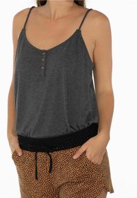 Top grigio senza maniche con scollatura rotonda, bottoni frontali e cintura elastica nera, abbinato a pantaloni corti arancioni macchiati.