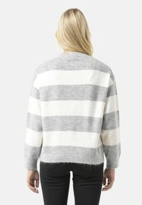 Pull rayé gris et blanc en tissu doux. Il présente un col rond, des manches longues et une coupe courte avec une finition texturée.