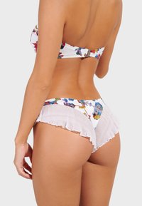 Bikini set se barevným květinovým vzorem na bílém pozadí, s texturovanými bílými volánky na spodní části, zobrazený ze zadní strany.