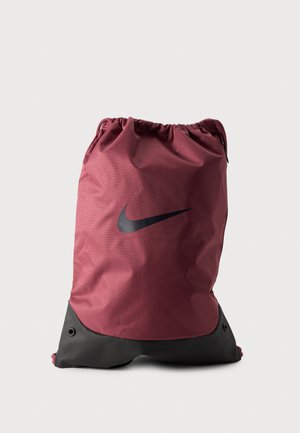 Bolsa Nike color burdeos con cordón, logotipo Swoosh negro y base negra reforzada, colocada sobre un fondo liso y claro.
