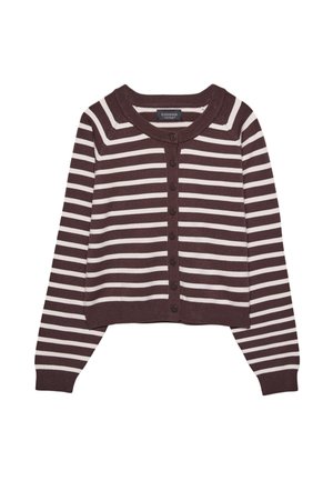 Femme portant un cardigan rayé marron et blanc, un pantalon large crème, et des chaussures marron à lacets sur un fond beige clair.