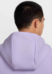 Felpa lavanda presenta un ampio cappuccio, una consistenza morbida e polsini a costine. Il design include una vestibilità morbida e dettagli sulla cucitura delle spalle.