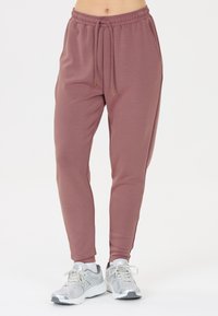 Roze joggers met een elastische tailleband, trekkoordsluiting en zakken. Grijze sportschoenen met veters en een gestructureerde zool.