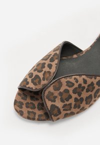 Leopard print open-toe sandals featuring a brown suede upper with black accents and a curved design for a sleek silhouette.