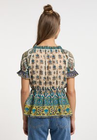 Blusa in tessuto leggero con motivo floreale, collo arricciato, maniche corte con volant e bordo a peplo svasato in tonalità blu e verdi.