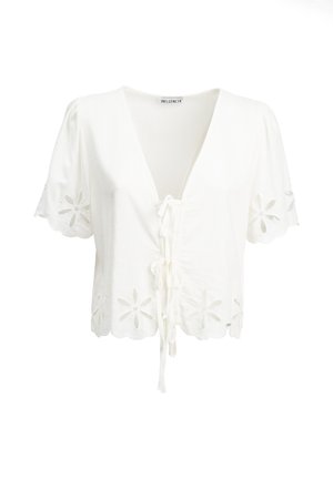 Witte blouse met korte mouwen, met bloemmotieven in ajour op de mouwen en zoom, veter aan de voorkant en gegolfde randen.