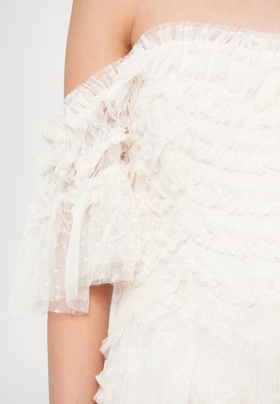 White off-shoulder top made of layered tulle with ruffled sleeves. Features a textured pattern and delicate lace accents.