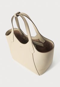 Bēšs ādas pleca soma ar diviem gariem rokturiem, atvērtu augšpusi, iekšēju rāvējslēdzēja kabatu un mīkstu brūna zamšāda iekšpuses oderējumu.