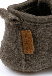 Brun filt sko med en strukturerad yta, med en stickad kant och en beige läderetikett präglad med "miki-line."