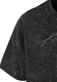 Mørkegrå oversized T-shirt med en tekstureret, falmet udseende. Har et subtilt, broderet logo i en lysere nuance på forsiden.