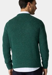 Zelený pletený svetr s texturovaným, tečkovaným vzorem. Má kulatý výstřih a pružné manžety, je pohodlně střižený a má středně dlouhé rukávy.