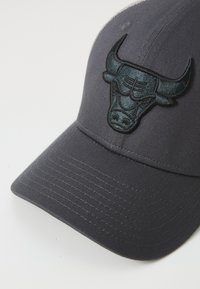 Black cap featuring a raised, embroidered bull head logo on the front, with a structured visor and textured fabric.