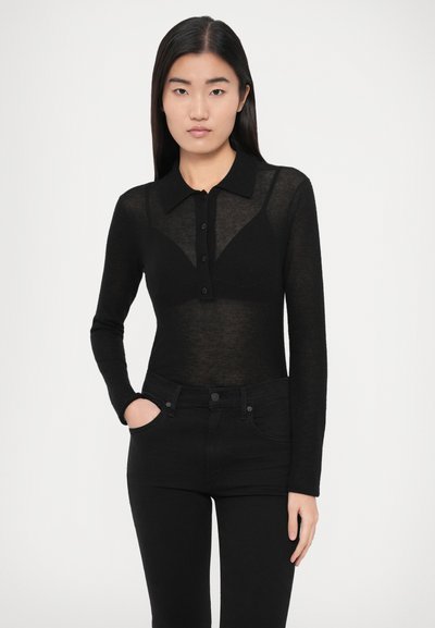 Μαύρο μακρυμάνικο τοπ με γιακά, διαθέτει κούμπωμα με κουμπιά και διαφανή υφή, σε συνδυασμό με μαύρο τζιν ψηλόμεσο.