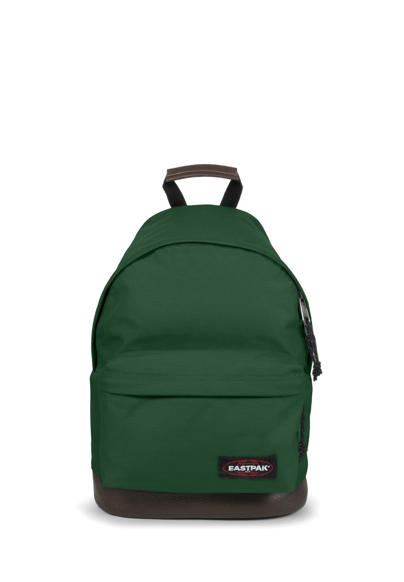 Grön tygryggsäck med rundad form, brun botten, framficka med dragkedja och en svart logopatch. Justerbara svarta remmar.