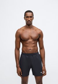 Čierne plavkové šortky s elastickým pásom, s malým logom na dolnej pravej strane. Hladká textúra a dĺžka po kolená.