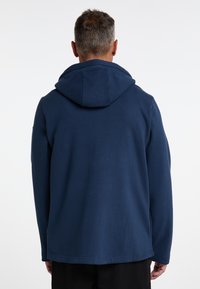 Sweatshirt à capuche bleu marine avec une texture douce, une coupe décontractée et une poche kangourou. La capuche est grande, avec un subtil détail de couture.