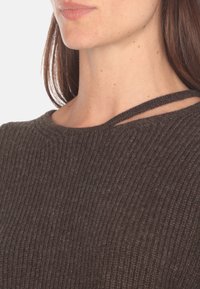 Maglione in maglia a coste marrone con scollo a barca e tagli sottili sulle spalle, che mette in mostra un design testurizzato e accogliente.