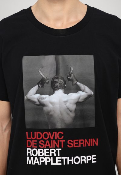 Schwarzes Baumwoll-T-Shirt mit einem grauen Fotodruck eines nackten Rückens mit Hörnern. Darunter in rot und weiß der Text mit den Namen der Künstler.