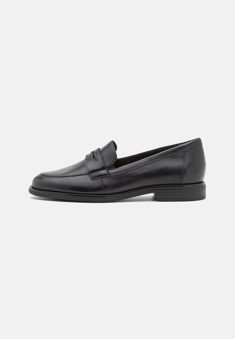 Mocassin noir en cuir à enfiler avec petit talon et détails cousus, présenté de profil sur un fond clair uni.