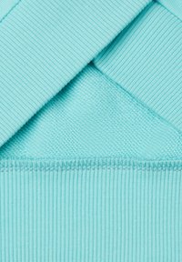 Light blue fabric with ribbed and smooth textures layered over each other, featuring a straight hem and neat stitching.