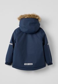 Marineblå parka med hætte med pelskant, elastiske manchetter, reflekterende detaljer og et gråligt logo ved kanten. Glat, vandafvisende stof.