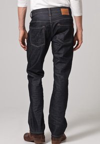 Mörkblå jeans i denim med rak ben och förstärkta sömmar samt detaljer med lappficka. Har en brun läderetikett på midjebandet.