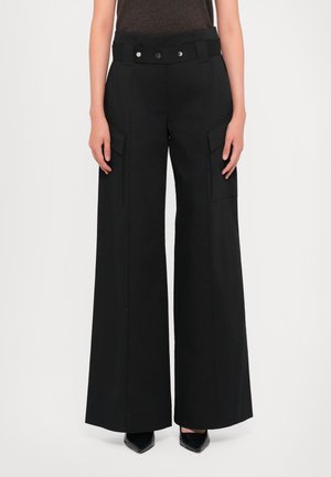 Pantalons larges noirs en matériau léger, avec une taille haute, deux poches plaquées à l'avant et une texture lisse.