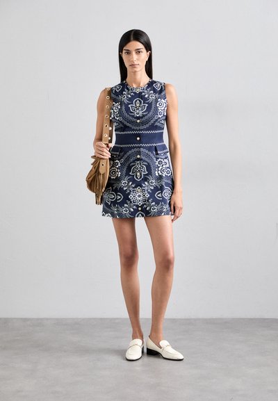 Rochie fără mâneci de culoare bleumarin cu modele florale albe, cu un corset ajustat și o fustă evazată; asortată cu o geantă din franjuri maro și mocasini albi.