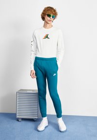Nike Sportswear CLUB JGGR - Tracksuit bottoms - geode teal/white