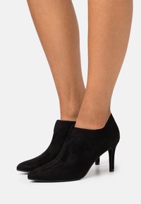 Bottines en daim noir avec un bout pointu et un talon aiguille de 7,5 cm. Dotées d'un design supérieur sans coutures, d'une texture douce et d'un minimum de garnitures.