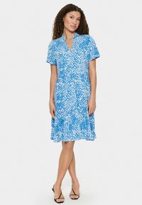 Kurzärmliges Kleid mit Kragen, mit einem blau-weißen abstrakten Muster, fließendem Rock und leichtem Stoff.