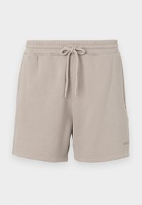 Pantalones cortos de algodón beige con cintura elástica y cordón. Cuenta con bolsillos laterales y un detalle de logo en el dobladillo. Textura suave.