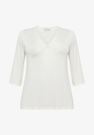 Valge, pika varrukaga topp, mis on valmistatud pehmest kangast. Omab V-kujulist kaelust ja keerdkuju esiosas. Omab lõdva siluetti ja sileda tekstuuri.