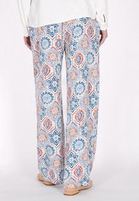 Gestreepte wijde broek met een hexagonaal patroon in blauw, oranje en wit. Gemaakt van lichte stof; heeft een luchtige textuur.