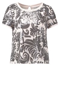 Blouse blanche à manches courtes avec motifs floraux noirs complexes et tourbillonnants et une petite fermeture à bouton dans le dos au niveau de l'encolure.