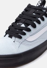 Αθλητικό παπούτσι από γκρίζο σουέντ με μαύρα κορδόνια, λευκή πλαϊνή λωρίδα και παχιά μαύρη σόλα, εμφανίζεται σε κοντινή λεπτομέρεια.