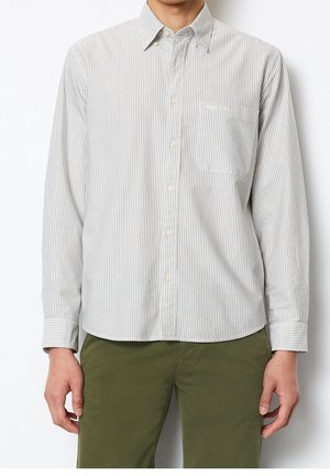 Homme portant une chemise boutonnée à rayures verticales gris clair et blanc avec une poche poitrine et un pantalon vert olive.