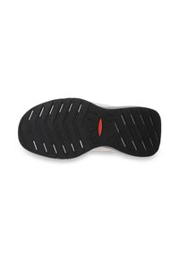 Semelle de chaussure en caoutchouc noir avec des rainures horizontales et un petit logo ovale rouge près de la voûte plantaire, vue du dessous sur fond blanc.