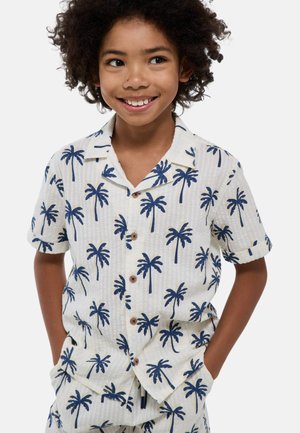 Chemise à manches courtes en tissu blanc avec un motif de palmiers bleu marine, dotée d'un col, d'une fermeture à boutons sur le devant et d'un détail de texture.