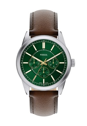 Montre en acier inoxydable avec un cadran texturé vert, des aiguilles dorées et un bracelet en cuir brun. Elle dispose de trois sous-cadrans et de marqueurs d'heure blancs.