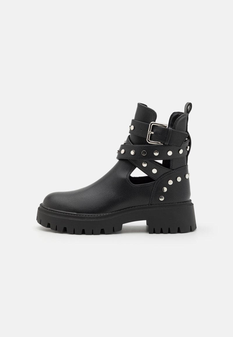 Bottines noires en cuir lisse, dotées de brides cloutées, d'une boucle, d'un design ajouré et d'une semelle en caoutchouc épaisse.