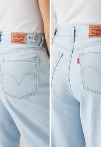 Light blue denim jeans featuring a Levi Strauss & Co. leather logo patch, two rear pockets, and classic stitching on the back.